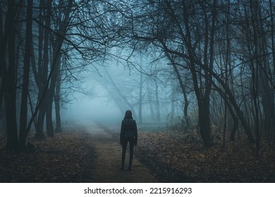 Girl on the road in a mysterious forest. Background wallpaper. Strange forest in a fog. Mystic atmosphere. Dark scary park. Paranormal another world. Gothic witch. - Powered by Shutterstock