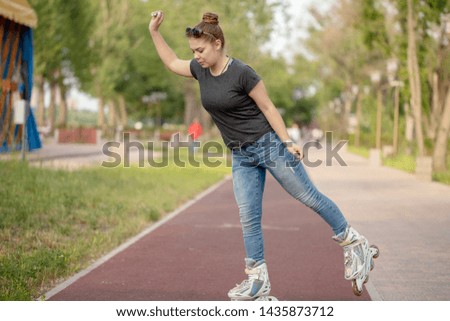 Girl on roller skates rides on the path of the city Park in the summer
