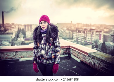 Girl on the roof of high building with cityscape behind