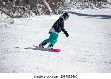 girl on a snowboard rides down the side of the mountain