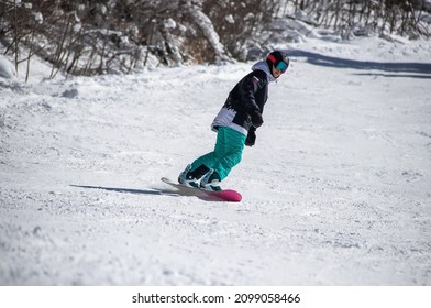 girl on a snowboard rides down the side of the mountain