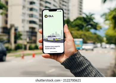 Girl on the street holding smartphone with Ola Cabs app on the screen waiting for car to arrive. Rio de Janeiro, RJ, Brazil. February 2022.