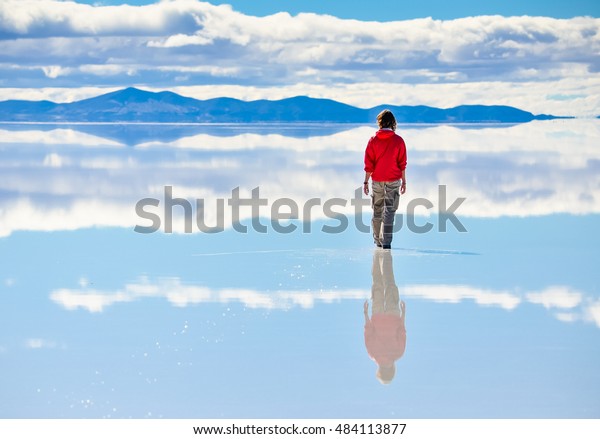 ボリビアのソルトレーク サラル ド ウユニの水面に空を反射した女の子 の写真素材 今すぐ編集