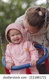 Girl on swing with mother in park
