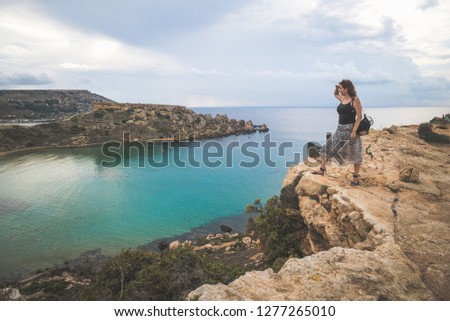 Girl on top of a cliff watching and admiring the sea view, Malta