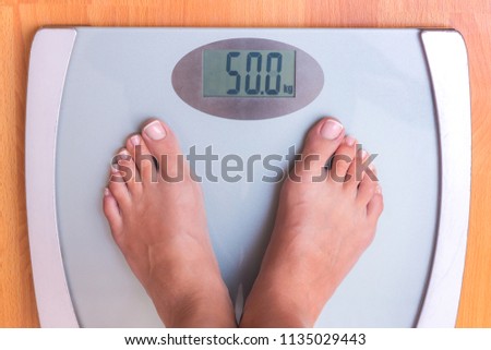 Girl on weighing. Perfect weight for a girl. Libra shows that a girl weighs 50 kg. Weight control