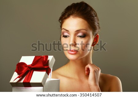 Girl opening x-mass present isolated on grey background