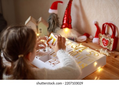 A girl opens a box of an original advent calendar with golden numbers from 1 to 24, New Year's crafts, gift boxes for every day, magical moments, a Christmas miracle in every home, gifts for Christmas - Shutterstock ID 2207103029
