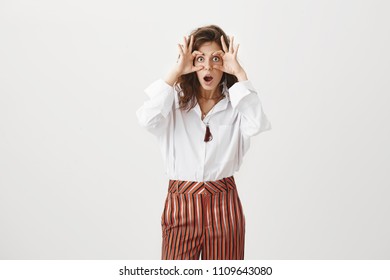 Girl Opens Eyes To See Truth, Making Shocking Revelation. Funny Attractive Woman In Stylish Blouse And Trousers, Stretching Eyelids And Staring With Popped Eyes At Camera While Gasping From Amazement