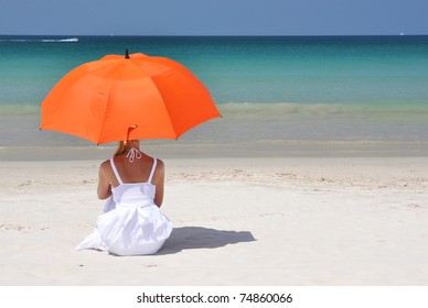 Girl With An Orange Umbrella On The Sandy Beach