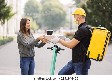 Girl Ordered The Delivery Of Pizza. Attractive Young Delivery Guy Holding Boxes With Hot Pizza And Two Cups Of Hot Drink Coffee. Friendly Delivery Man Handing Pizza To A Customer.