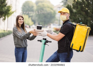 Girl Ordered The Delivery Of Pizza. Attractive Young Delivery Guy Holding Boxes With Hot Pizza And Two Cups Of Hot Drink Coffee. Friendly Delivery Man Handing Pizza To A Customer.