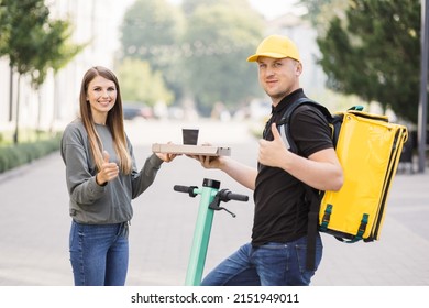 Girl Ordered Delivery Of Pizza. Attractive Young Delivery Guy Holding Box With Hot Pizza And Cup With Hot Drink Coffee. Friendly Delivery Man Handing Pizza To A Customer.