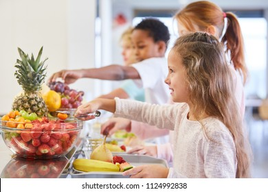 Girl and other kids at the fruit buffet at the cafeteria in elementary school