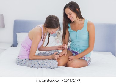 Girl Painting Her Friends Nails On Bed At Girls Night