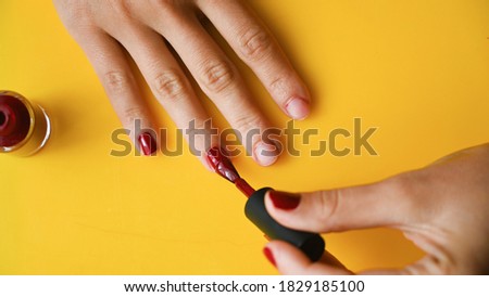 Girl paints her nails with red varnish