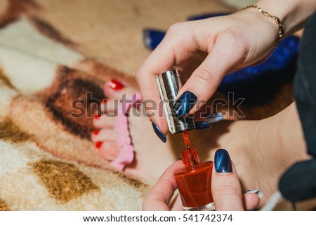 The girl paints nails, legs, a varnish