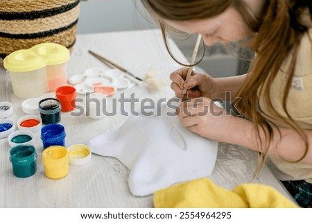 The girl paints the quadrober's mask with paints.