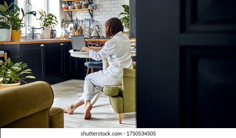 A Girl In Pajamas Is Working On A Laptop From Home In The Kitchen. Home Environment. Cozy Home. Long Banner With Copy Space. Work Remotely.