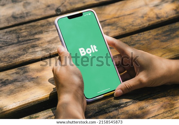 Girl in the park holding a smartphone with Bolt\
mobility company app on the screen. Rustic wooden table. Rio de\
Janeiro, RJ, Brazil. May\
2022.
