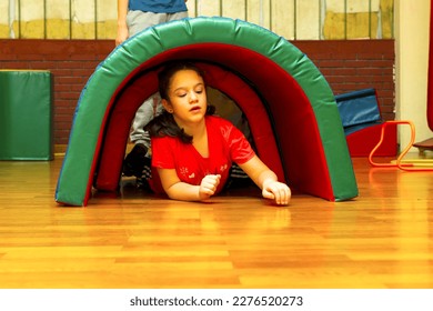 Girl pass under course of barriers on his fours. Concept of development of fine motor skills, tactile sensations, creativity, children's entertainment. - Powered by Shutterstock