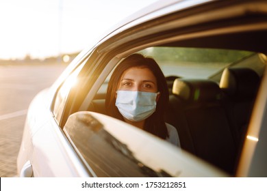 Girl Passenger In Protective Sterile Medical Mask In The Taxi Car During An Epidemic In Quarantine City. Health Protection, Safety And Pandemic Concept. Covid - 19. 