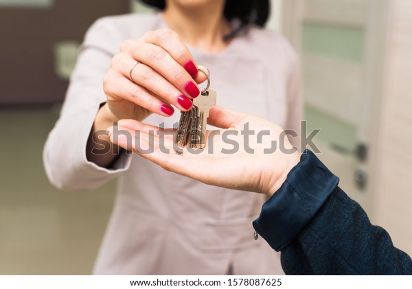 The girl passes the keys to the house or office\
in the hands of another person. The concept of the sale of real\
estate, housing, office\
rental.
