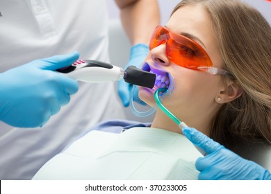 Girl Patient In The Dental Clinic. Teeth Whitening UV Lamp With Photopolymer Composition.