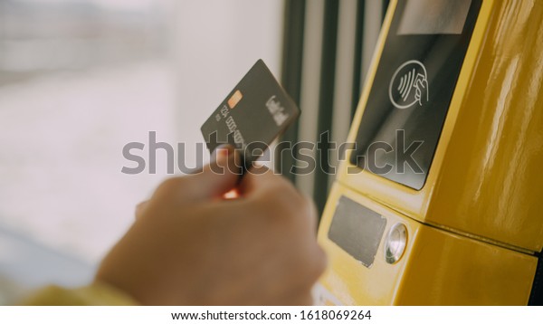 Girl paying conctactless with bank card for the\
public transport in the\
tram