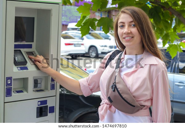 Girl paying for\
parking her car outdoors