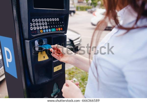 girl pays the ticket to the parking place\
of the car and the payment of the fare on the way. Concept of new\
technologies in road transport and toll\
roads.
