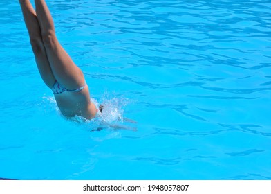 Girl Performing Synchronised Swimming And Diving In Blue Water