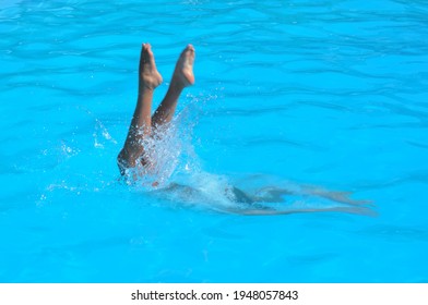 Girl Performing Synchronised Swimming And Diving In Blue Water