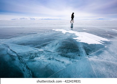 Girl photographer walking on cracked ice of a frozen lake Baikal