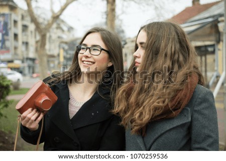 Similar – Image, Stock Photo Twin sisters take pictures of each other with smartphone at a bridge railing