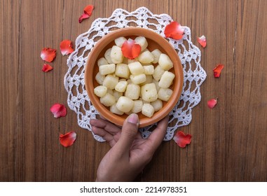 A girl picking up Chena Murki in a bowl, Chena Murki is a bite-size dry sweet made with paneer dipped in sugar syrup  - Shutterstock ID 2214978351