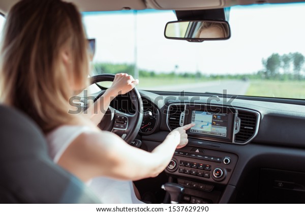 girl\
in pink car driving car selects an application on touch screen\
display, turns on selects navigation, chooses route, parks outside\
city, sets route before starting to move in\
nature