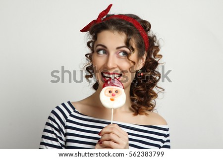 Girl pin-up posing with candy in his hand in the studio.