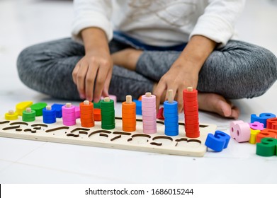 Girl placing the blocks that a geometrical montessori puzzle of colors