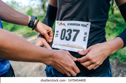 Girl placing the race number with the help of a teammate - Powered by Shutterstock