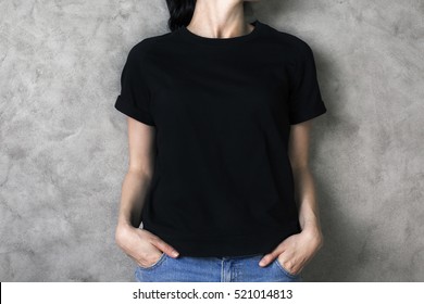 Girl in plain black shirt and jeans on concrete backgroud. Mock up