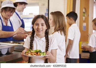 Girl with plaits holding plate of food in school cafeteria