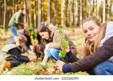 Girl plants a tree seedling as a climate change tree with family in the background