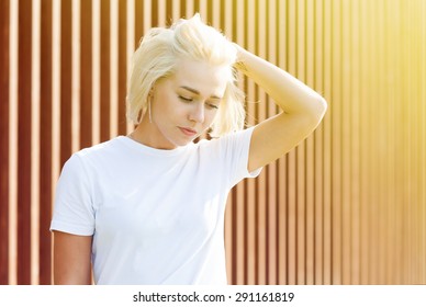 Girl With Platinum Blond Hair In White T-shirt On Woden Background With Flare