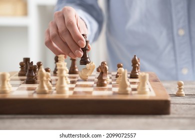 Girl player performs a knight chess piece move. On the chessboard there is a brown board made of natural wood. A female hand holds a horse figure.
 - Shutterstock ID 2099072557