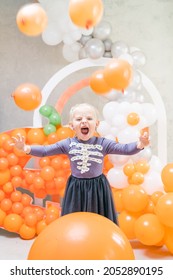 Girl Playing With Balloons In Front Of Halloween Party Decorations. DIY Skeleton Costume.