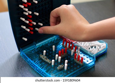 Girl Playing In The Board Game Battleship, Toy War Ships And Submarine. Selective Focus.