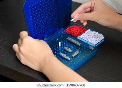 Girl Playing In The Board Game Battleship, Toy War Ships And Submarine. Selective Focus.