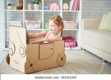 Girl Playing With Car Made Of Cardboard Box