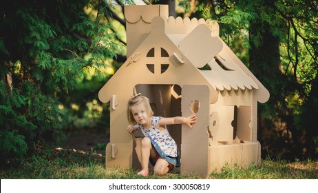 Girl Playing Cardboard House In A City Park On A Sunny Day